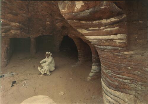 [Seated Bedouin at entrance to a storehouse, Petra] [picture] / [Frank Hurley]