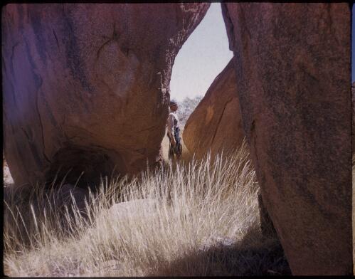 [Unidentified man standing in a rock structure, Devils Marbles, Northern Territory] [transparency] / [Frank Hurley]