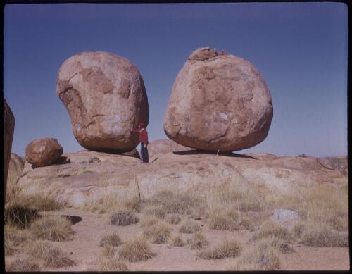 [Unidentified man standing next to two rocks, Devils Marbles, Northern Territory] [transparency] / [Frank Hurley]
