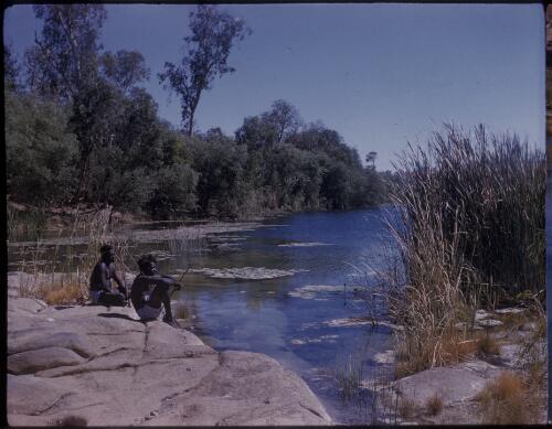 [Two Aboriginal men sitting on rock by a river, Northern Territory] [transparency] / [Frank Hurley]