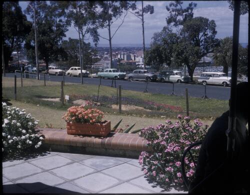 [Row of parked cars in front of a view of Perth, Western Australia] [transparency] / [Frank Hurley]