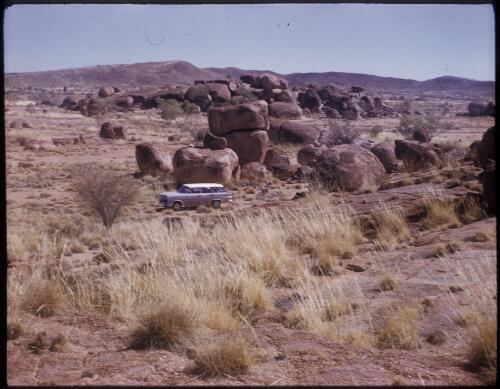 [Grey Holden station wagon parked amongst large boulders, Northern Territory] [transparency] / [Frank Hurley]