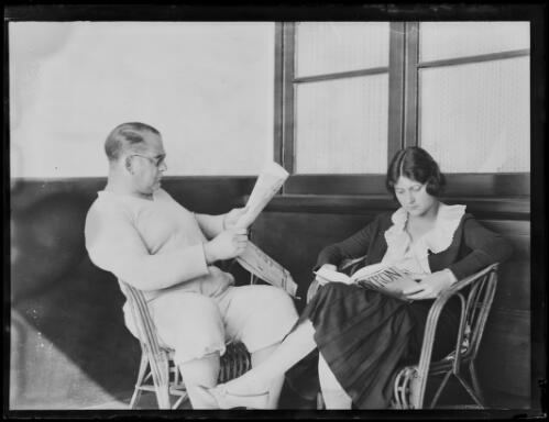 American wrestler Ed Strangler Lewis and his wife sitting in chairs reading at their Bondi flat, New South Wales, 23 August 1930 [picture]