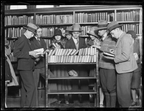 Group of men and women gathered around a trolley full of books at the Municipal Library, New South Wales, 20 June 1930 [picture]
