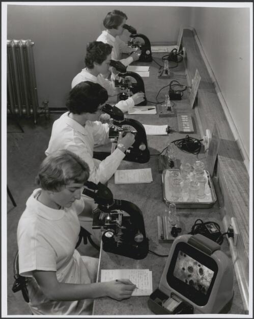Skilled technicians study slides of cells in body fluids, looking for abnormalities suggestive of cancer at the Royal Womens Hospital, Melbourne, 1959 [picture] / Wolfgang Sievers