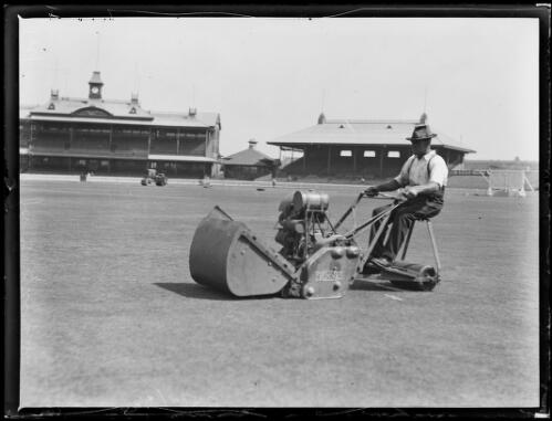 Man operating a lawn mower and roller at the Sydney Cricket Ground in preparation for the visiting English team, Sydney, 23 November 1932 [picture] / Baden H. Mullaney