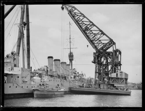 H.M.A.S. Melbourne docked next to a crane in Sydney Harbour, Sydney, ca. 1920s [picture]