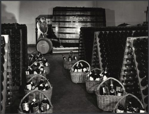 Bottles of champagne displayed in wicker baskets and shelves at Penfolds' champagne cellars, Auldana, South Australia, 1958 [picture] / Wolfgang Sievers