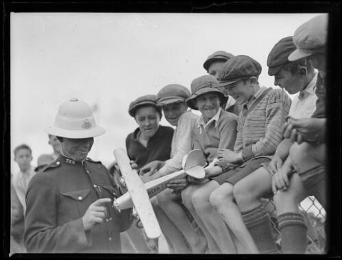 Aviator F. C. Chichester playing with a model plane watch by a crowd of children, Sydney, 1931 [picture]
