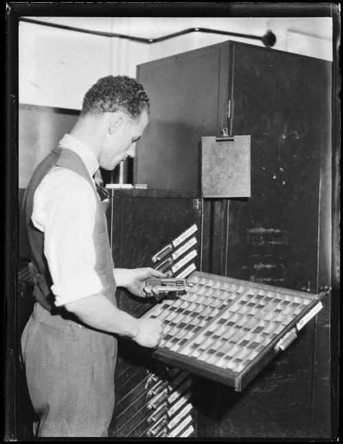 Man examining a drawer of typefaces in the Sun newspaper machine room, Sydney, 11 October 1934 [picture]