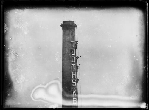 Member of the steeplejacking Meyer family waving from the top of the Austral Brickworks tower, Sydney, ca. 1923 [picture]