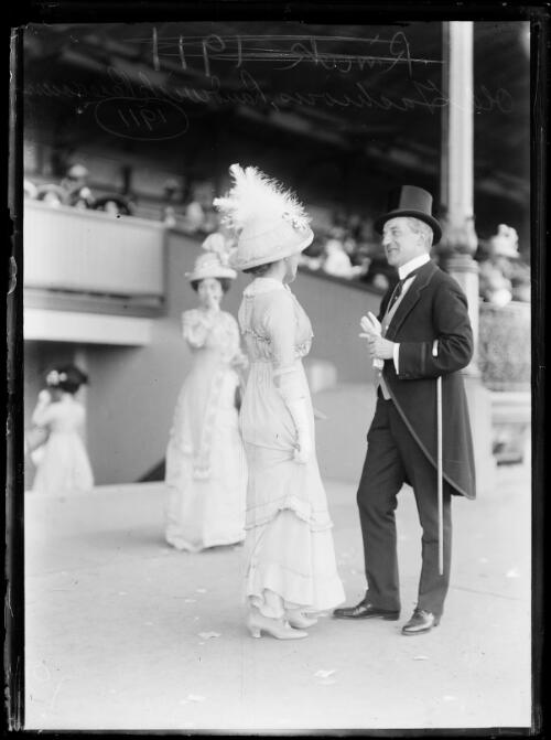 Woman in a gown and hat talking to a man in tails and a top hat, Randwick, New South Wales, 1911 [picture]
