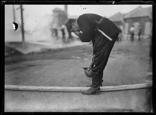 Firefighter with an axe in his belt and a hose between his feet, New South Wales, ca. 1930s [picture]