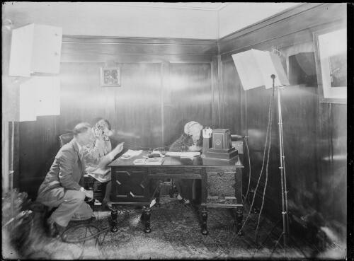 Mary Kingsford-Smith talking to Charles Kingsford-Smith via wireless telephone with two men in a room, Sydney, ca. 1930 [picture]