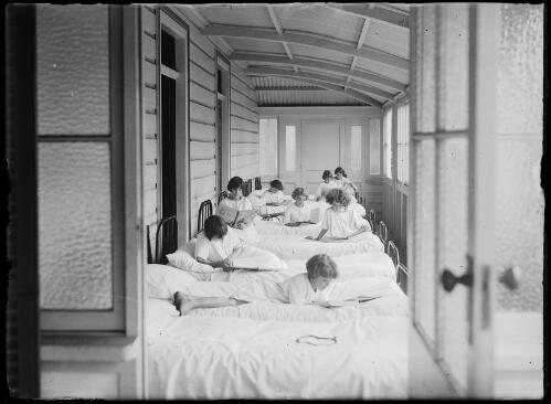 Eight young girls reading on a line of beds in an orphanage, New South Wales, ca. 1930s [picture]