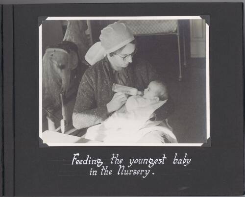 [Photograph of nurse bottle] feeding the youngest baby in the nursery [picture]