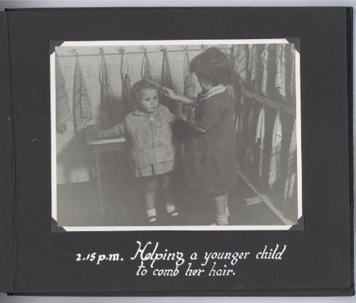 [Photograph of child helping comb another younger child's hair] at 2.15 p.m. [picture]