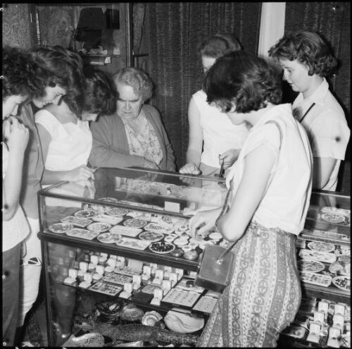 A group of women looking at opal jewellery on display, Alice Springs, Northern Territory, May 1961 / Michael Terry