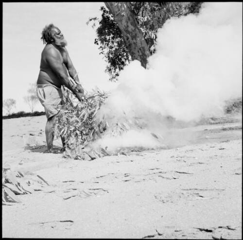 Aboriginal Australian man making smoke, Alice Springs region, Northern Territory, 1961 / Michael Terry
