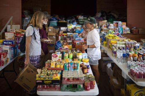 Volunteeer Laura Holmes assisting local residents browsing for goods at the Quaama Town Hall, Quaama, New South Wales, 10 January 2020 / Sean Davey