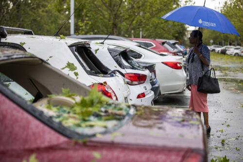 Gail Barry standing behind her damaged car in a public car park after a hailstorm, Parkes, Canberra, Australian Capital Territory, 20 January 2020 / Sean Davey