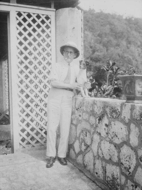 A man and his dog standing on the veranda, Christmas Island, approximately 1920