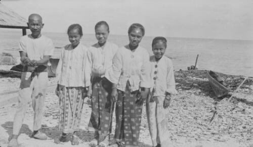 A Christmas Islander man and four girls standing next to each other on the beach, Christmas Island, approximately 1920