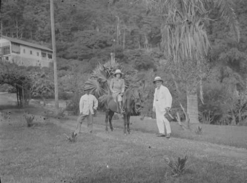 Two man standing next to a woman on horseback, Christmas Island, approximately 1920