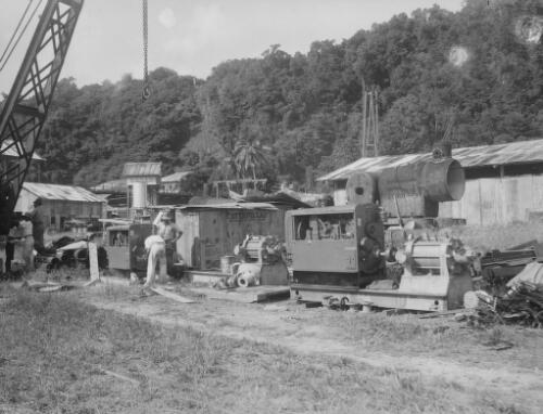 Two employees inspecting parts at the Christmas Island Phosphate Company machinery yard, Christmas Island, approximately 1927