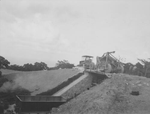 Two Christmas Island Phosphate Company earth moving machinery crossing a railway bridge with stationery hopper wagons parked underneath, Christmas Island, approximately 1927, 3