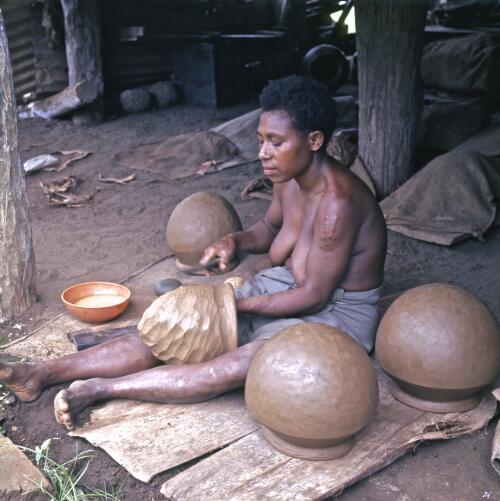 A potter at Yabob Ceramics Centre beating out pots for firing, Madang, Papua New Guinea, approximately 1968 / Robin Smith