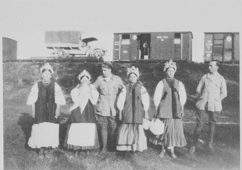 Four women in national costume with two soldiers standing in front of a railway train, Russia, approximately 1918, 2 / Michael Terry