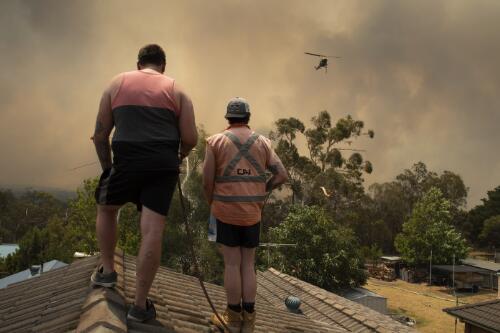 Two men hosing a rooftop protecting property from a bushfire burning out of control, New South Wales, 21 December 2019 / Matthew Abbott