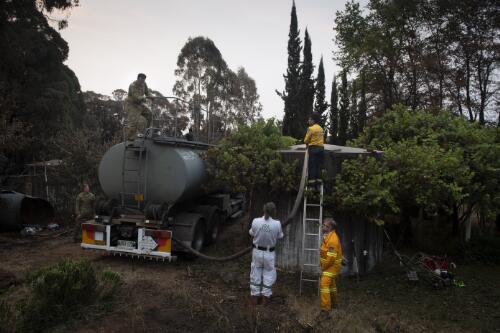 Volunteer firefighters Edmund Blenkins, Michael Blenkins and two army officers filling the watertank on thier property with a mobile watertank truck, near Batlow, New South Wales, 9 January, 2020 / Matthew Abbott