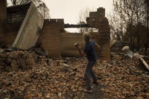 David Strohfeldt throwing a brick at his property destroyed from the New Year's Eve bushfires that swept through the main street of Cobargo, New South Wales, 24 January, 2020 / Matthew Abbott