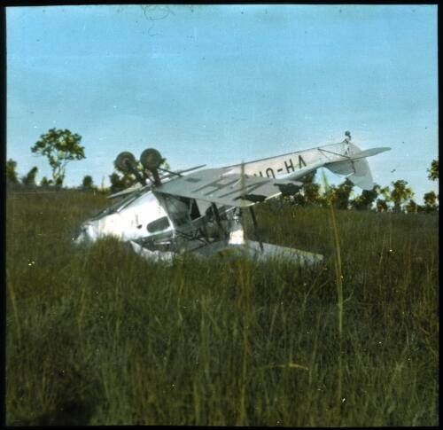 Dr Jean White's Royal Flying Doctor Service De Havilland Fox Moth biplane [VH-URI] air ambulance upside down in paddock [transparency] : Fred McKay Cape York Peninsula and West Queensland Patrol 1938-1940 / [Fred McKay]