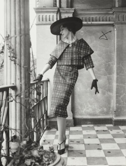 A model in a dress and hat standing on a balcony, approximately 1968 / Athol Shmith
