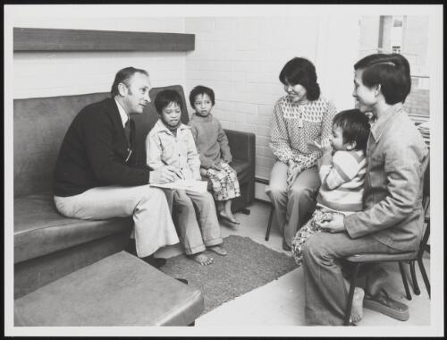 Housing officer, Mr Tony Destradi talking with a Vietnamese father and his children, Melbourne, Victoria, 1979 / Australian Information Service photograph by Patrick McArdell