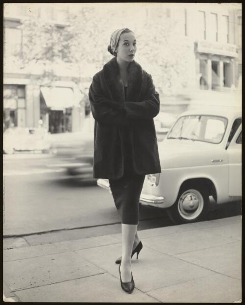 Model wearing a coat and skirt in the street, approximately 1954 / Athol Shmith