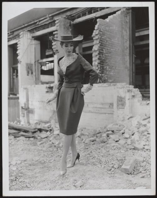 Diane Masters wearing a skirt, jacket and a large hat, approximately 1960 / Athol Shmith