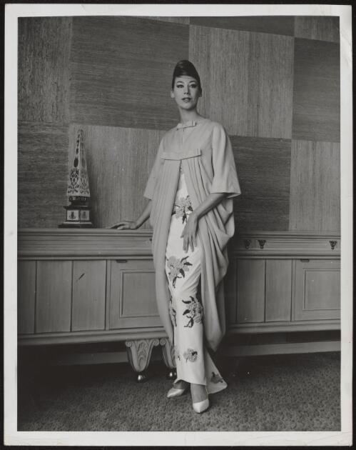 Diane Masters wearing an oriental style embroidered dress and coat, approximately 1960 / Athol Shmith