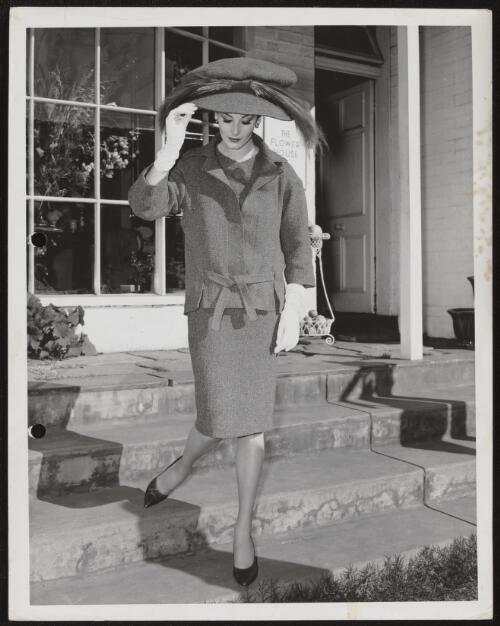 Model on the steps of a shop called the Flower House, approximately 1960, 1 / Athol Shmith