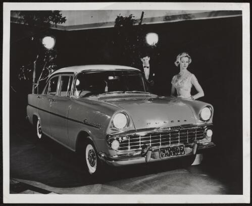 Male and female models in evening dress standing next to an EK Holden Special, 1961 / Athol Shmith
