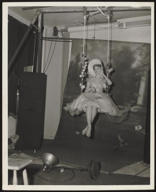 Fashion model on flower decorated swing, approximately 1965 / Athol Shmith