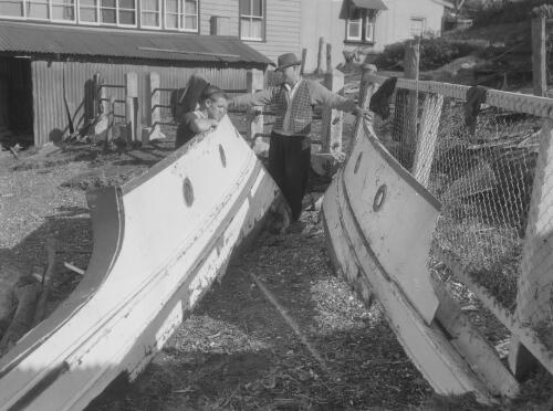 Two men observing debris washed up during floods from Lake Macquarie, Coal Point, New South Wales, 26 June 1949