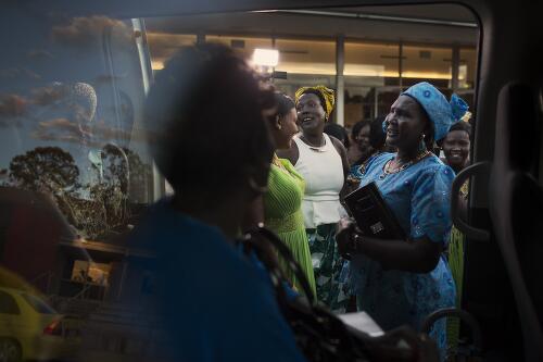 At a bride price ceremony, women from the Dinka Yirrol tribe representing the groom, near a minivan filled with the bride's female family members, Sydney, 2015 / Conor Ashleigh