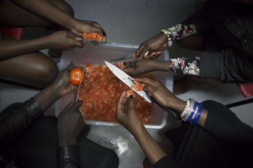 Sudanese teenage girls dicing tomatoes at a bride price ceremony, Sydney, 2013 / Conor Ashleigh