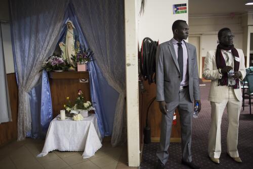 Two men standing at the door to welcome community members attending the 30th anniversary of the Sudan People's Liberation Army, Sydney, May 2013 / Conor Ashleigh