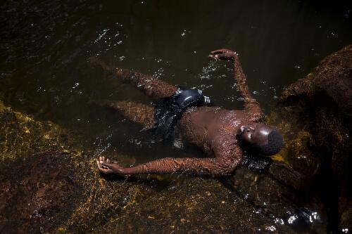 Acuoth Acol lying in a rock pool at Empress Falls, Blue Mountains National Park, New South Wales, 2015 / Conor Ashleigh