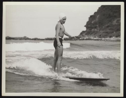 A woman surfer standing on a surfboard, Sydney, approximately 1935